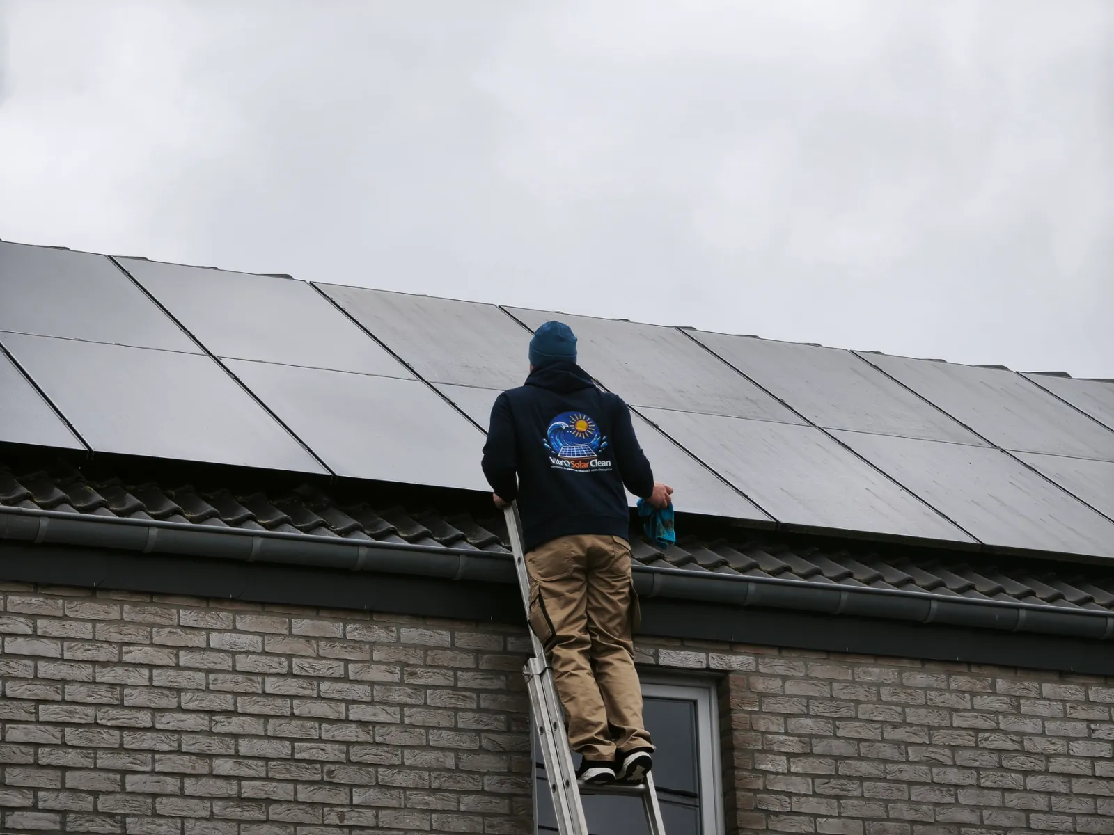 Technicien Vitro Solar Clean nettoyant des panneaux solaires sur une toiture en Hainaut, Wallonie