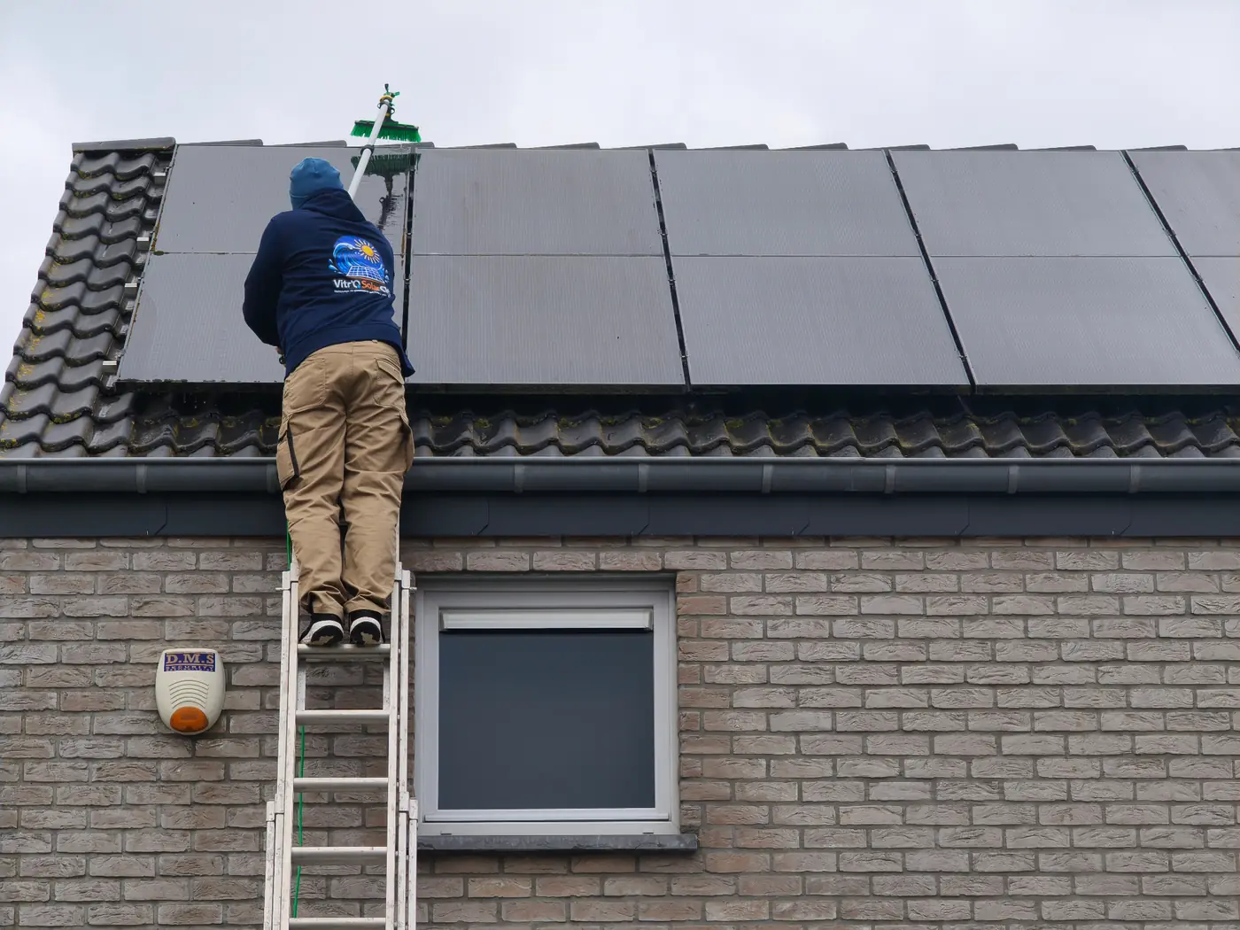 Technicien Vitro Solar Clean nettoyant des panneaux solaires à la perche eau pure sur toiture en province de Namur