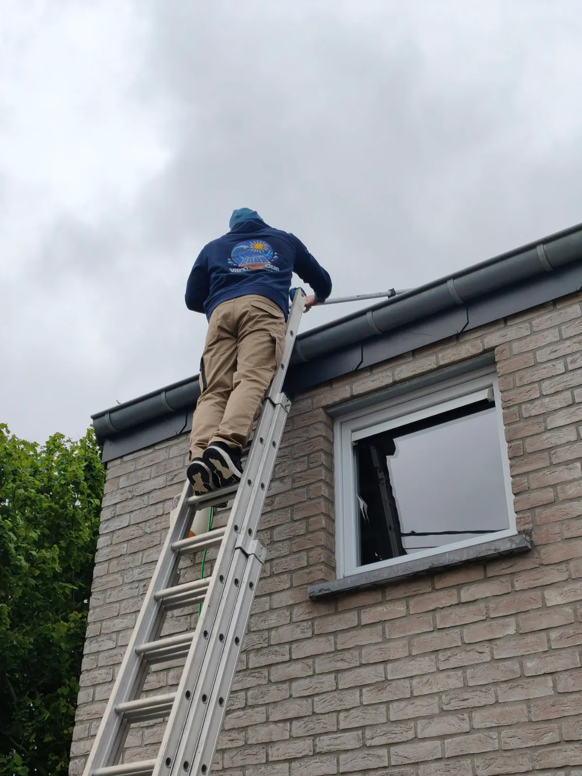 Technicien ex-pompier Vitro Solar Clean au travail sur une perche carbone à eau pure en Hainaut au printemps